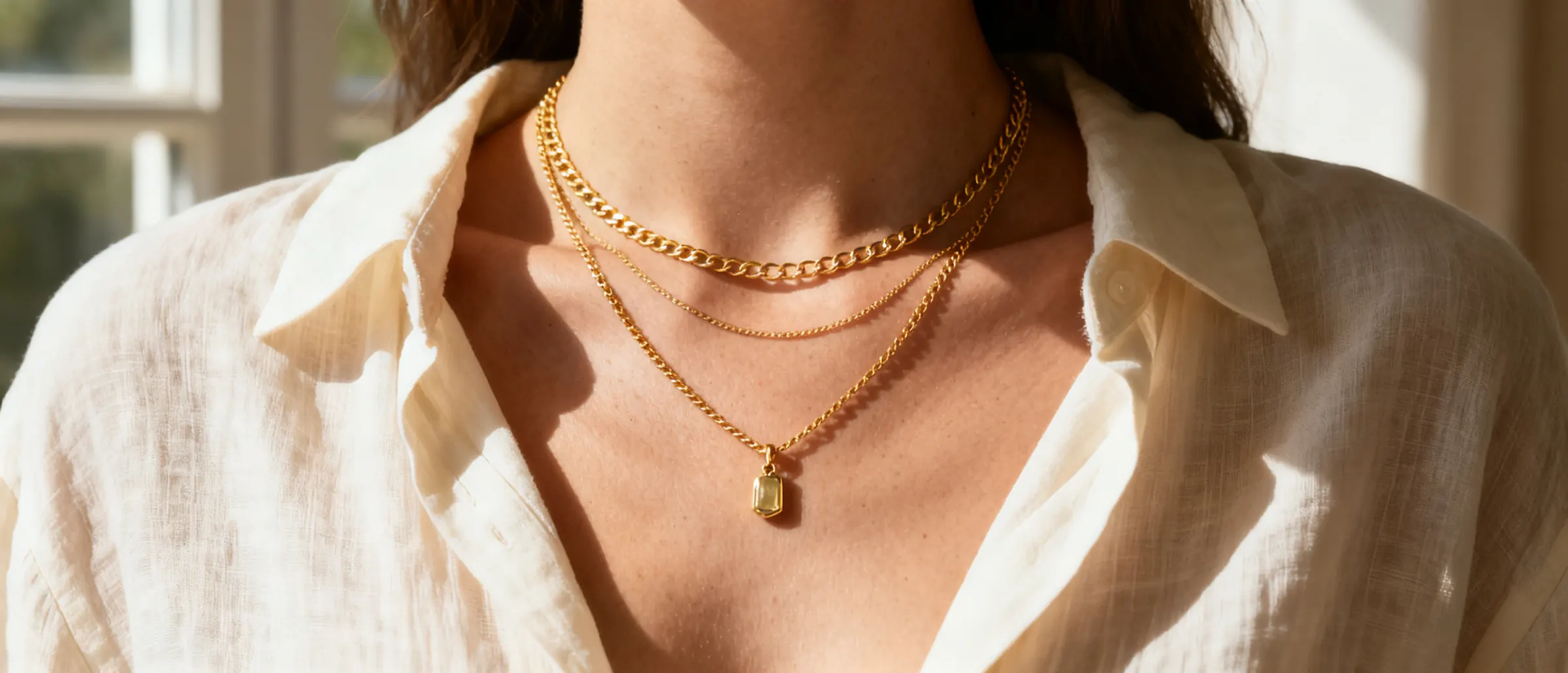A woman's collarbone with a fine layered necklace in warm afternoon light